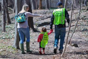 Volunteers wearing yellow vests collect trash near Doan Brook.