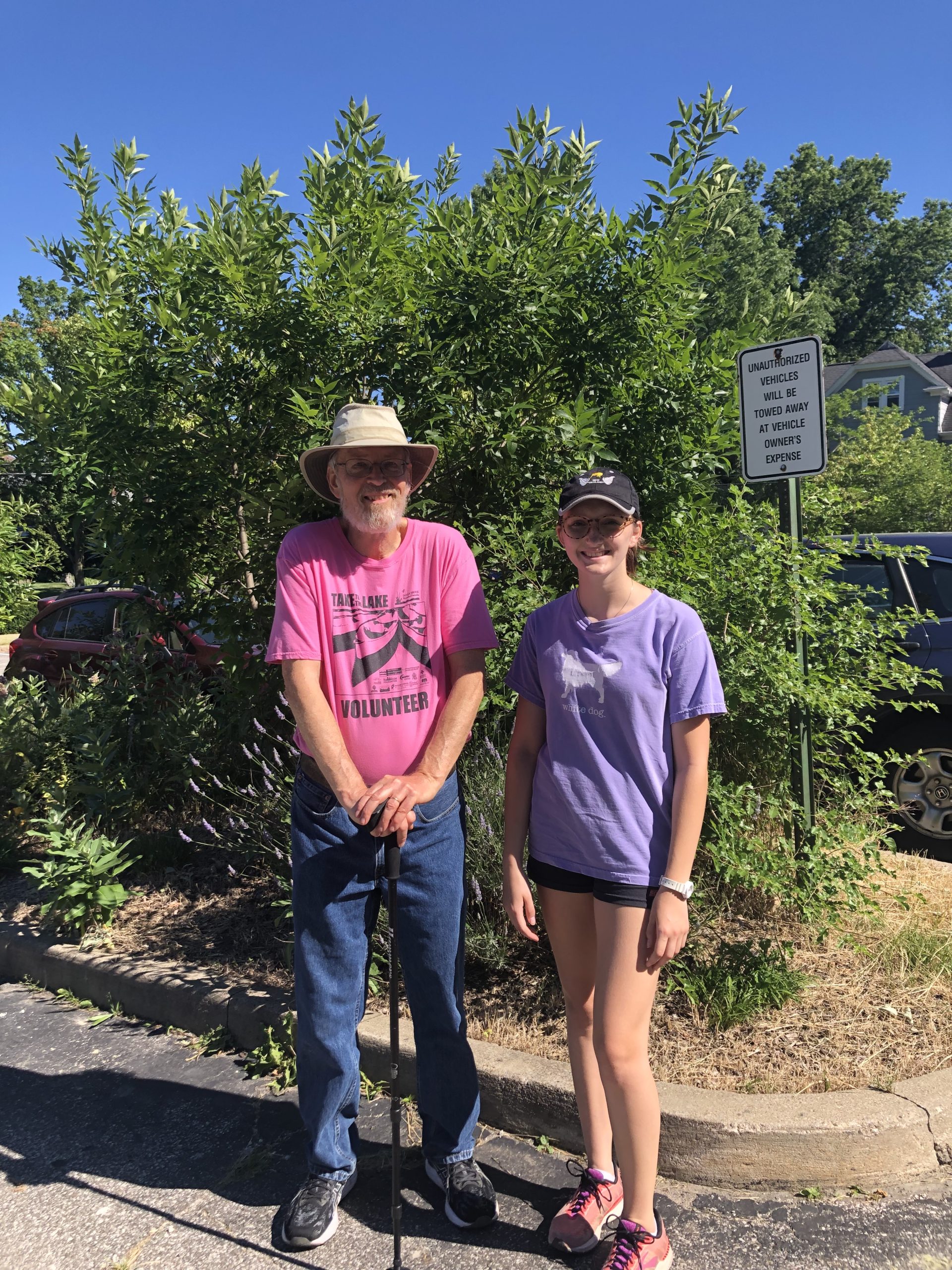 Sydney Knight and John Reebel pose in front of a bush.