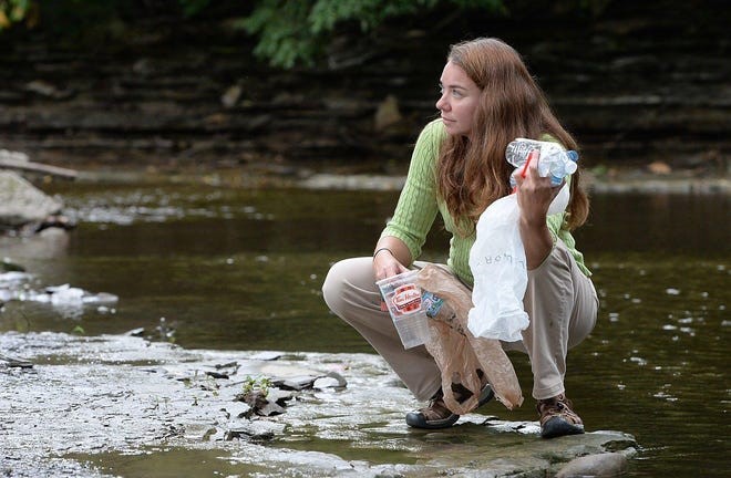 Dr. Sherri Mason picking up plastic in a stream.